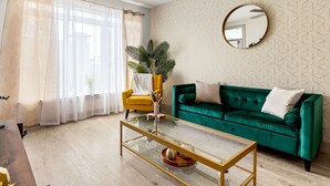 A living room with a green sofa, a glass coffee table, a yellow armchair, and a large mirror on the wall. - Riverwalk Luxe Apartment, Stunning pool, King Bed (San Antonio)