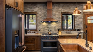 Una cocina moderna con protector contra salpicaduras de piedra, electrodomésticos de acero inoxidable y armarios de madera.