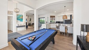 A modern living room with a pool table, a dining area, and a kitchen with dark backsplash. - Waterfront Punta Gorda Isles Retreat: Private Pool & Charlotte Harbor Canal Access (Punta Gorda)