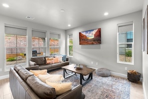 A spacious living room with a leather sofa, a coffee table, and a large painting on the wall.