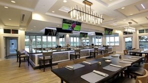 A modern restaurant with a bar area, multiple screens, and a view of the outdoors. - Luxurious golf home with pool in prestigious Colonial Country Club + Amenities (Fort Myers)