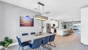 A modern kitchen with white cabinets, stainless steel appliances, and a central island with bar stools. - OCEANLUX-Luxury+Gulf_Access+Heated_Pool+Kayaks+Golf+Chefs_Kitchen+Games (Cape Coral)