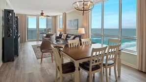 Une pièce spacieuse avec une grande table à manger, des chaises, un canapé et une vue sur l’océan.