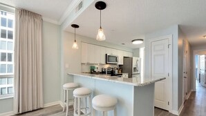 Une cuisine moderne dotée d’un îlot central, de tabourets de bar et de luminaires suspendus.
