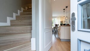 A modern kitchen with a central island, a dining area with chairs, and a staircase with wooden steps. - Haus Shelly - 3-zimmer Haus für 5 Personen: Terrasse, 2 Stellplätzen, Wlan. Haustier Erlaubt (Sylt-Ost)