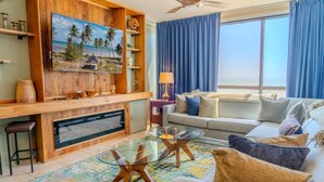 Una sala de estar con un televisor grande, un sofá, una mesa de centro y una chimenea.