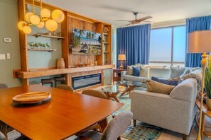 A living room with a wooden dining table, a sofa, a TV, and a ceiling fan.