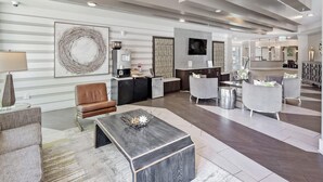 A spacious hotel lobby with a modern design, featuring a large abstract artwork, a reception desk, and contemporary seating areas. - Uptown 4th Ward Luxury Apt Year-round Pool (Charlotte)