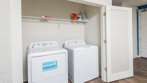 A laundry room with two front-loading washing machines and a closed door. - Uptown 4th Ward Luxury Apt Year-round Pool (Charlotte)