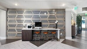 A modern bar area with a geometric patterned wall, a flat-screen TV, and three stools. - Uptown 4th Ward Luxury Apt Year-round Pool (Charlotte)