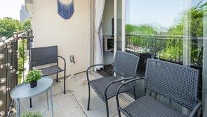 A balcony with two chairs, a small table, and a hanging macrame decoration. - Uptown 4th Ward Luxury Apt Year-round Pool (Charlotte)