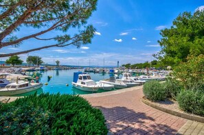 A marina with boats docked, a clear sky, and greenery around.