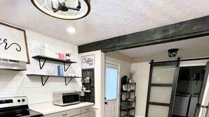 Une cuisine moderne avec un plancher en bois, des appareils électroménagers en acier inoxydable et un luminaire décoratif au plafond.