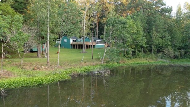 Un chalet au bord du lac, doté d’une terrasse et entouré d’une forêt dense et d’une étendue d’eau paisible.