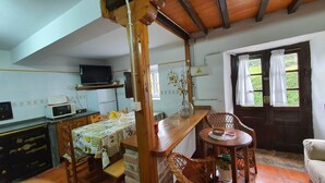 A cozy kitchen with a dining area, wooden furniture, a television, and a window with curtains.
