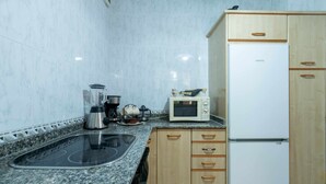 A kitchen with a granite countertop, a built-in stove, a microwave, a refrigerator, and wooden cabinets. - Casa la Aldea de Barro (Barro (Llanes))