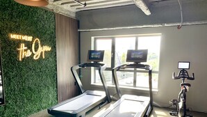 Una palestra con tapis roulant, cyclette e un neon.