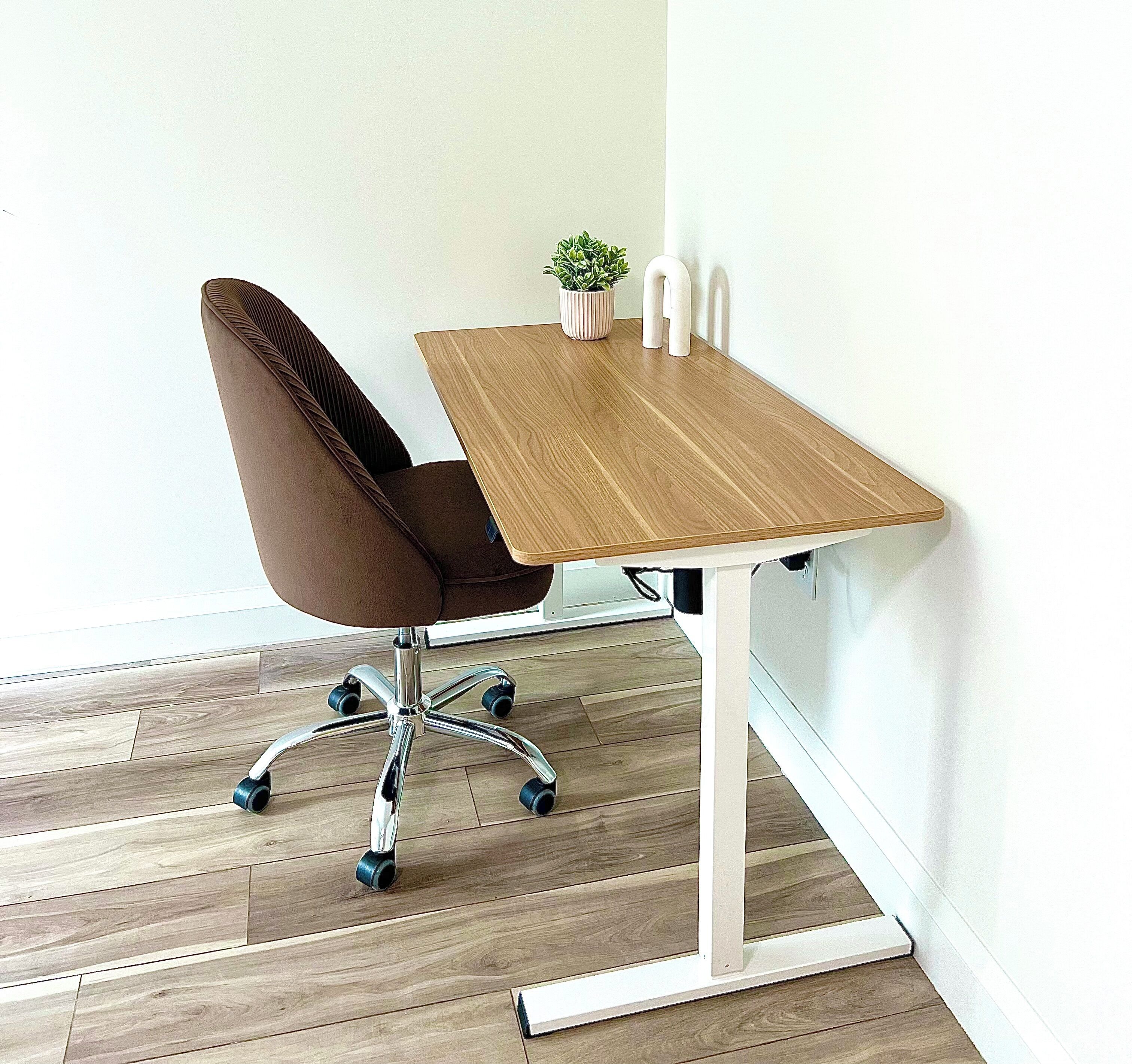A brown office chair with a high backrest and a metal base with wheels, positioned at a wooden table with a white base.