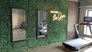 Una palestra con un muro verde, un tapis roulant e due specchi.