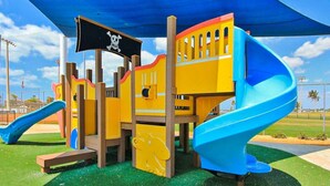 Une aire de jeux dotée d’une structure ludique sur le thème des pirates, comprenant des toboggans et des zones d’escalade.