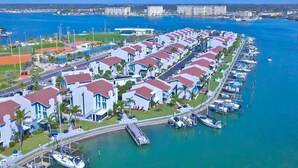 Un quartier résidentiel situé sur la côte, avec des maisons modernes, un port de plaisance et un terrain de sport.