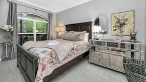 Quarto com cama grande, penteadeira, espelho e janela com cortinas.