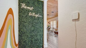Un couloir avec un mur vert, une peinture abstraite aux couleurs vives et un mur blanc sur lequel est accroché un téléphone.