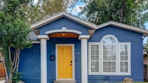 Une maison de plain-pied à l’extérieur bleu, avec une porte d’entrée jaune et le numéro 536 peint sur le mur.