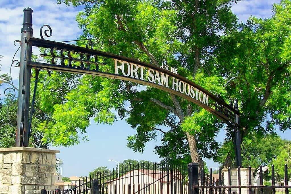 A street sign for Fort Sam Houston with a stone base and metal gate.