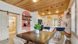 Une cuisine moderne avec un plafond en bois, des armoires blanches et un îlot central doté de tabourets de bar.