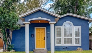 Stunning home with a distinctive architectural style, featuring a prominent front door, white columns, and a small porch.