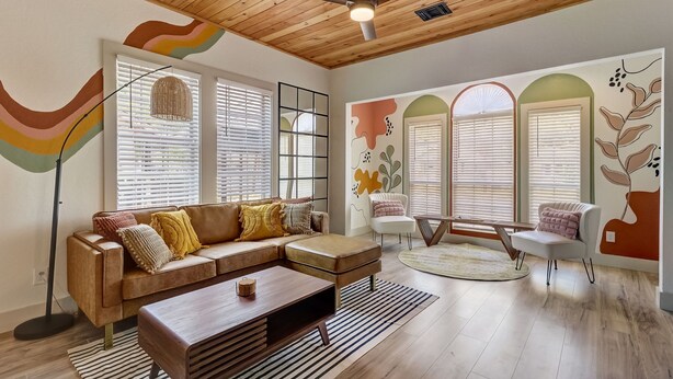 Un salon moderne avec un plafond en bois, un canapé d’angle, une table basse et un fauteuil blanc.