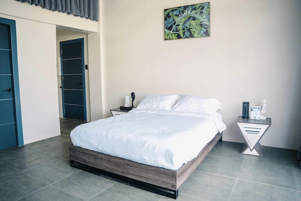 Ein Schlafzimmer mit einem Bett, einem Nachttisch, einem Wandbild und einer Tür.