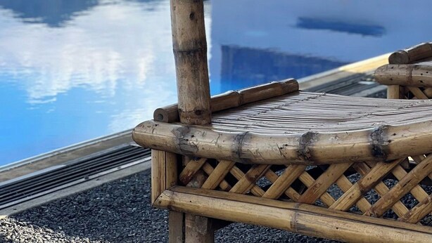 A pool area with a bamboo structure, a clear blue pool, and a view of a mountainous landscape. - Fight Club Philippines (Puerto Princesa)