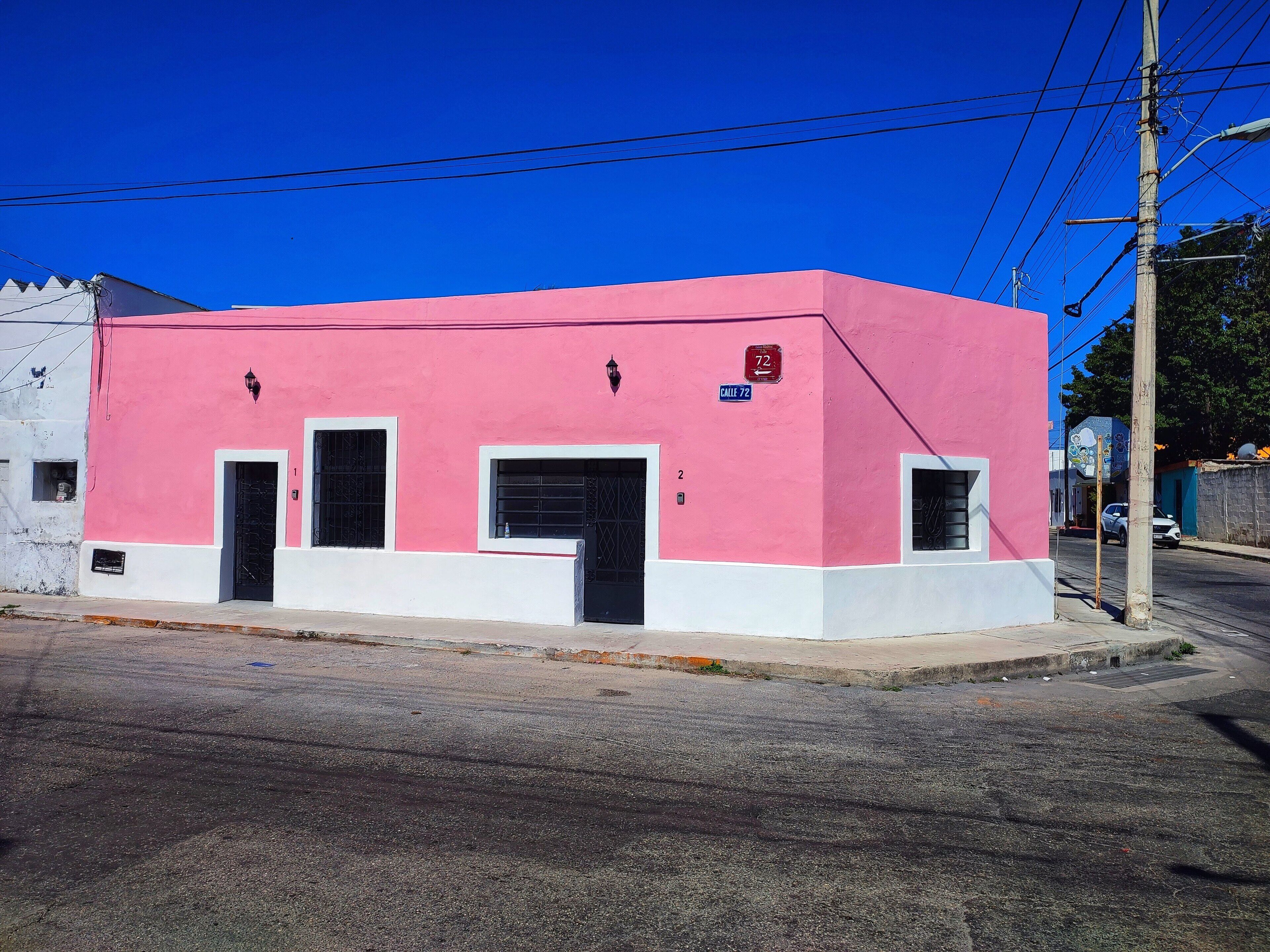 A pink building with two doors and windows, located at a street corner.