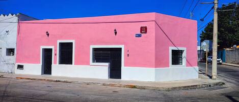 A pink building with two doors and windows, located at a street corner.