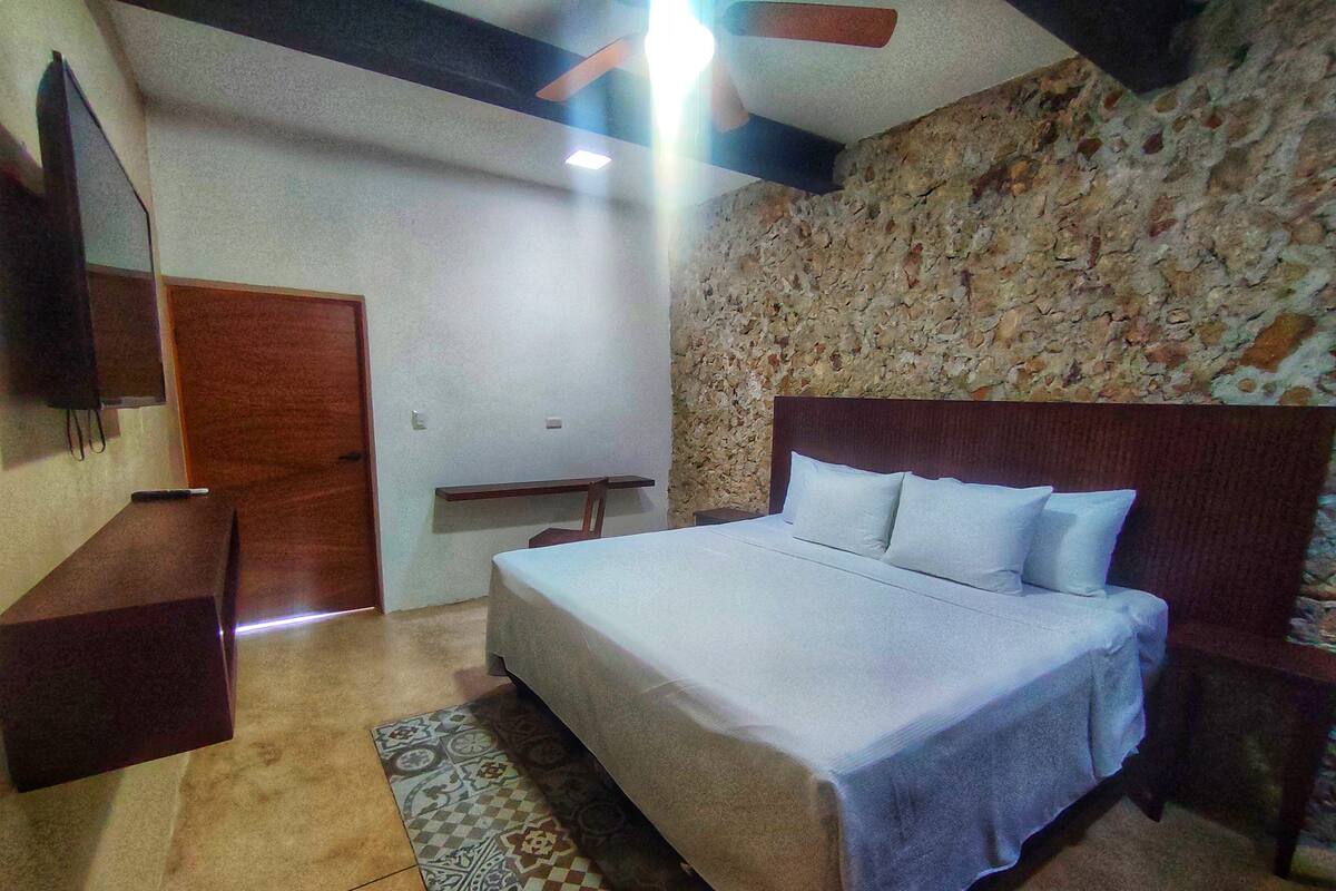 Une chambre à coucher avec un lit, un bureau, un miroir et un tapis à motifs.