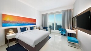 Ein modernes Hotelzimmer mit einem großen Bett, einem Schreibtisch, einem Stuhl und einem Fernseher.