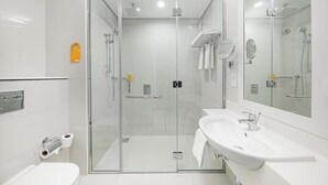 Ein modernes Badezimmer mit einer einteiligen Duschkabine, einem weißen Waschbecken und einer Toilette.