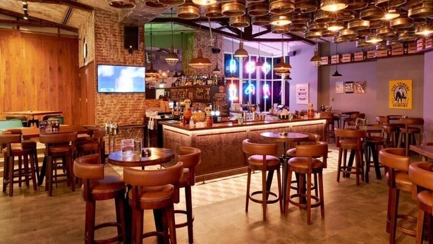 Eine Bar mit Holztischen, einer Theke und hängenden Lampen.
