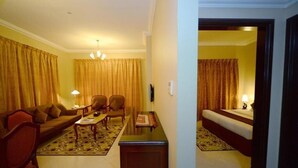 A hotel room with a sofa, chairs, a small table, a bed, and a carpeted floor. - Two Bedroom Apartment Near Al Khan Beach By E R (الشارقة)