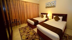 A hotel room with two beds, a large window with curtains, a patterned rug, and a wall art piece. - Two Bedroom Apartment Near Al Khan Beach By E R (الشارقة)