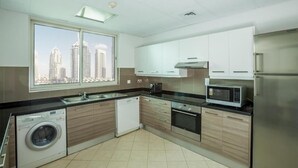 Een moderne keuken met een vaatwasser, wasmachine, magnetron, oven en een roestvrijstalen koelkast.