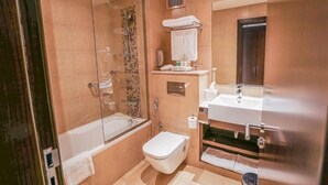 Et badeværelse med en bruseniche med glasvægge, et hvidt toilet og en vask med spejl.