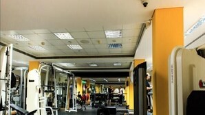 Et fitnesscenter med forskellig træningsudstyr og et overvågningskamera i loftet.