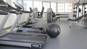 A gym with treadmills, weight machines, and a large exercise ball. - Studio Apartment Near Carrefour Tecom by E R (Dubai)