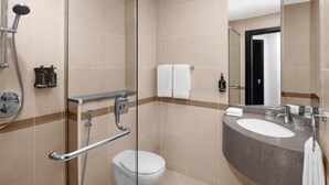 Uma casa de banho moderna com chuveiro de vidro, sanita branca, toucador com lavatório e um espelho grande.