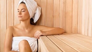 A person sitting on a wooden bench in a room with vertical wooden paneling.