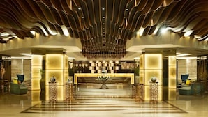 A spacious lobby with a central reception desk, decorative lighting, and modern furniture. - Standard Room In Business Bay By E R (Dubai)