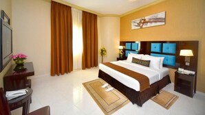 Habitación de hotel con una cama grande, un escritorio, una silla y un televisor.